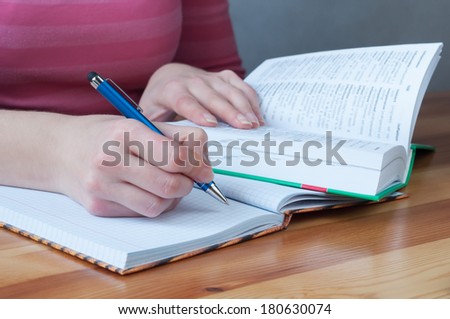 Writing with a pen in a notebook, learning with dictionary. Macro image with shallow depth of focus.