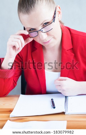 Young woman attentively observing from behind her glasses.