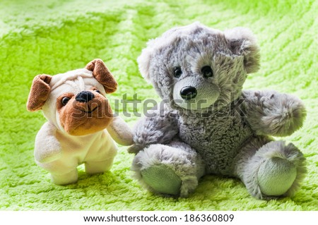 Plush puppy and teddy bear on green blanket.