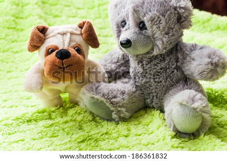 Plush puppy and teddy bear on green blanket.
