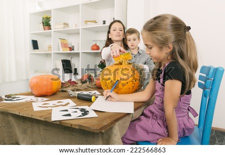 Mother and two children carving jack o lanterns on Halloween