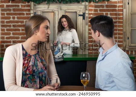 Smiling couple on a date at a bar, man flirting with a waitress...