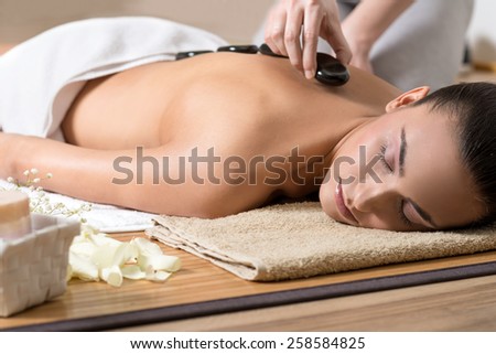 Woman Enjoying Hot Stone Ritual in Spa Center