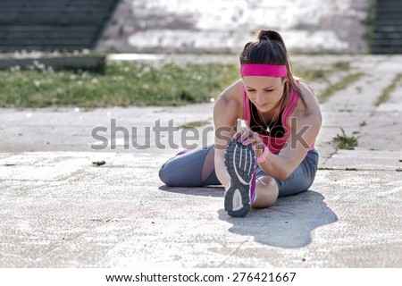 Woman doing  warm-up exercises before running.Photo is carefully post processed to mach old Kodak  film look.Soft focus, shallow depth of field.
