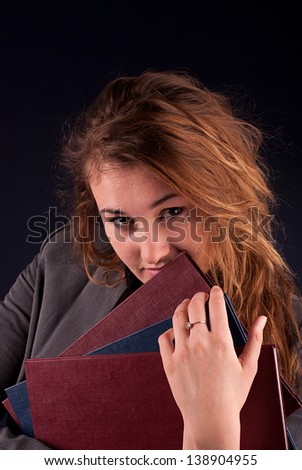 Young woman with books on the dark background