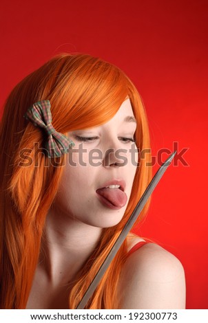 Beautiful young girl with red-orange hair licking katana