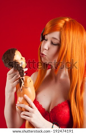Beauty redhead woman with ugly doll