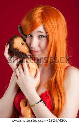 Beauty redhead woman with ugly doll