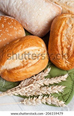 Freshly baked traditional rolls on cotton cloth with ears of wheat grain