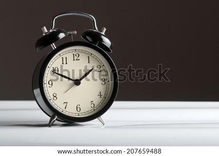 Black vintage alarm clock on dark background