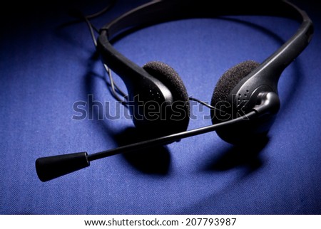 Black headphone with microphone on dark blue background