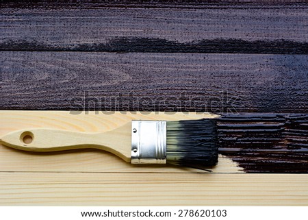 Wet paint brush lying on brown planks