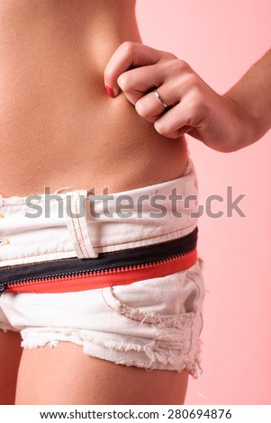 Close up of pretty woman pinching skin of her hip