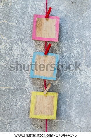 wooden picture frame hanging on clothesline on cement background.