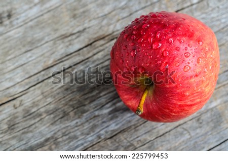 red apple on wooden table with water drops