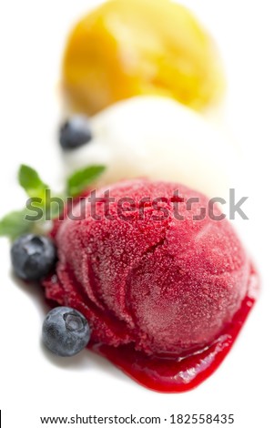 Vivid melted ice-cream scoops with blueberry and mint leaf, isolated on white, shallow DOF