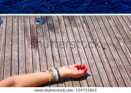 Female hand with jewelery on the deck of a sailing yacht, at the Aegean sea, Greece