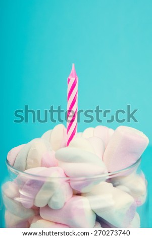 The sweet marshmallows in glass jar with candle