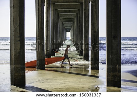 SAN DIEGO, CALIFORNIA - MARCH 31: Unidentified man dragging a canoe boat walking through the Scripps Pier on March 31, 2013 in La Jolla, San Diego, CA, USA.  La Jolla Shore is a popular launch point for canoeing.