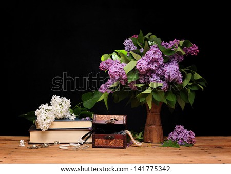 Lilac in a ceramic vase, books and jewelry