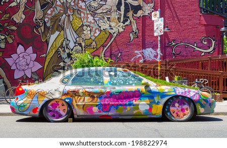 TORONTO, CANADA - JUNE 7, 2014: A car down Kensington Market covered in Grafitti and plants growing from the bonnet