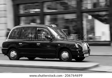 LONDON, UK - 16TH MARCH 2014: A Taxi moving down a street in London with people on the street in the background