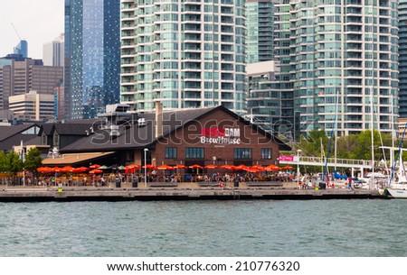 TORONTO, CANADA - 11 AUGUST 2014: The outside of the Amsterdam Brewhouse Restaurant from Lake Ontario. People can be seen outside on desk chairs
