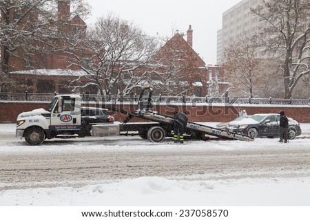 TORONTO, CANADA - 11TH DECEMBER 2014: A vehicle being being rescued in the snow during the day. People can be seen