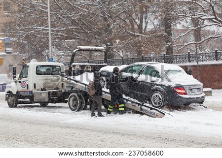 TORONTO, CANADA - 11TH DECEMBER 2014: A vehicle being being rescued in the snow during the day. People can be seen