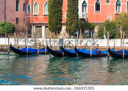 Gondolas in Venice during the day. Colourful Buildings can be seen behind them.