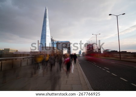 LONDON, UK - 25TH MARCH 2015:  Rush hour in London showing the blur of people walking, a London red bus, The Shard and other buildings