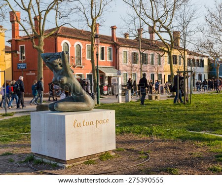 BURANO, ITALY - 14TH MARCH 2015: La Tua Pace statue near Burano port. Large amounts of people can be seen in the distant