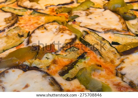 A closeup to vegetarian pizza toppings. Zucchini, green peppers and cheese can be seen.