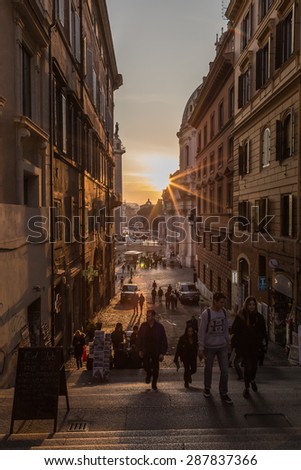 ROME, ITALY - 11TH MARCH 2015:  A view down Via Magnanapoli in Rome at sunset, showing architecture and people. The sun can be seen in the distance.