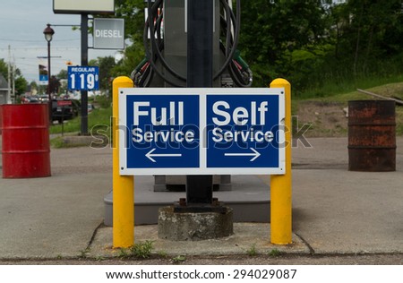 A sign at a gas station instructing people to go to the left for Full Service or the right for Self Service pumps