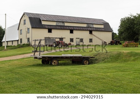 CAPE BRETON, CANADA - 5TH JULY 2015: The outside of a Barn with lots of Farm equipment outside during an overcast day in the summer