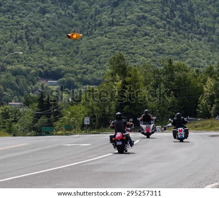 CAPE BRETON, CANADA - 4TH JULY 2015: Motorcyclists on a road in Cape Breton during the summer with hills in the background.