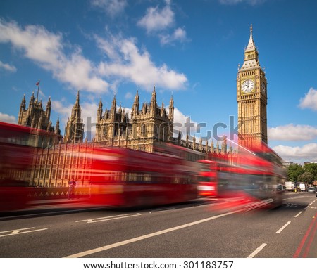 Big Ben in Westminster with red London Buses going past during the day. There is space for text in the image