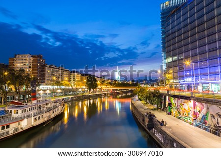 VIENNA, AUSTRIA - 21ST AUGUST 2015: A view along the Danube Canal shortly after sunset. People, buildings and bars can be seen.