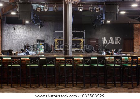 bar counter with bar chairs in loft style design, strobe light on dark ceiling