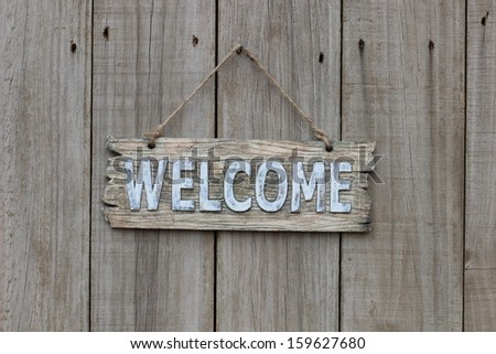 Rustic wood welcome sign hanging on old weathered fence