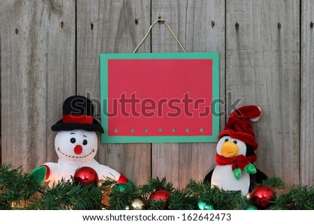 Holiday sign with snowman and penguin with garland and ornament border