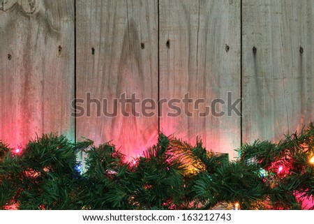 Green garland with colored lights on wooden fence