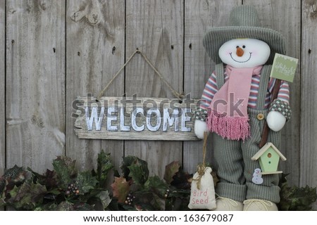 Wood welcome sign with snowman in green overalls with garland border