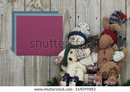 Snowman and moose sitting by fence with blank sign