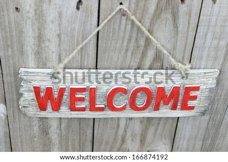 Wood welcome sign hanging on wood fence