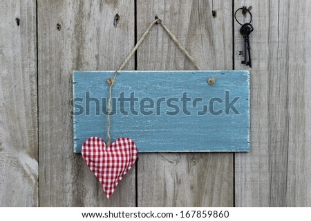 Antique blue sign hanging on wood door with red heart and iron keys