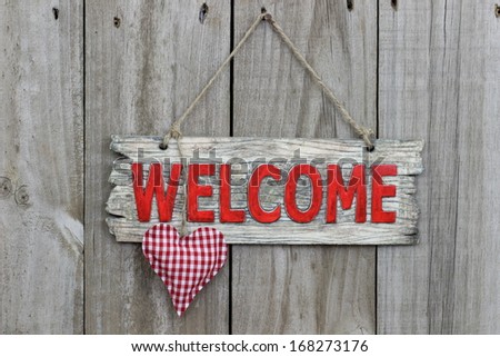 Red welcome sign hanging on wood door with gingham heart