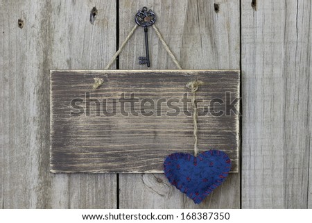 Blank wood sign hanging on door with blue calico heart and iron key