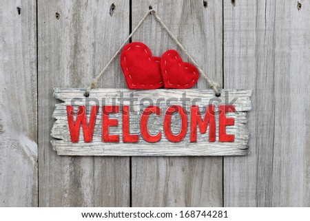 Red welcome sign hanging on wood door with red hearts
